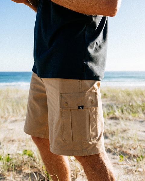 Person wearing beige shorts and a navy shirt on a beach
