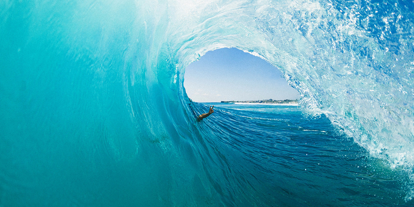 Surfer riding a large blue wave in the ocean