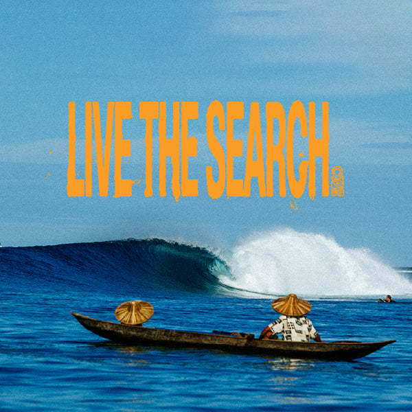 Two people in a boat with hats on, watching a large wave in the ocean with 'Live the Search' text overlay.