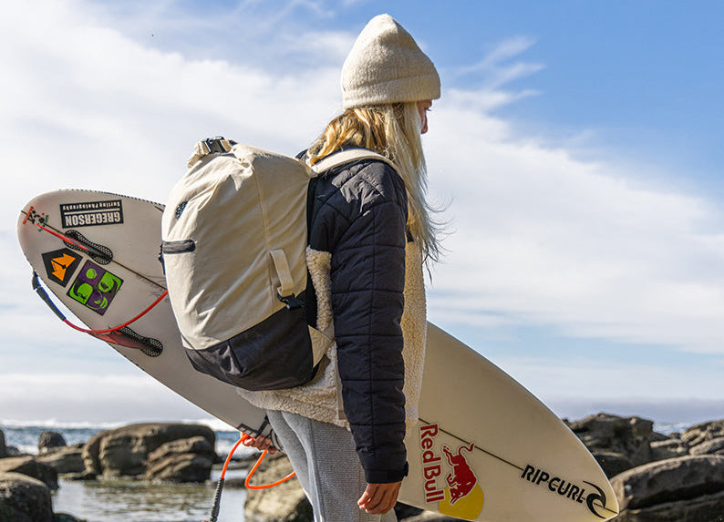 Woman with a backpack and a surfboard